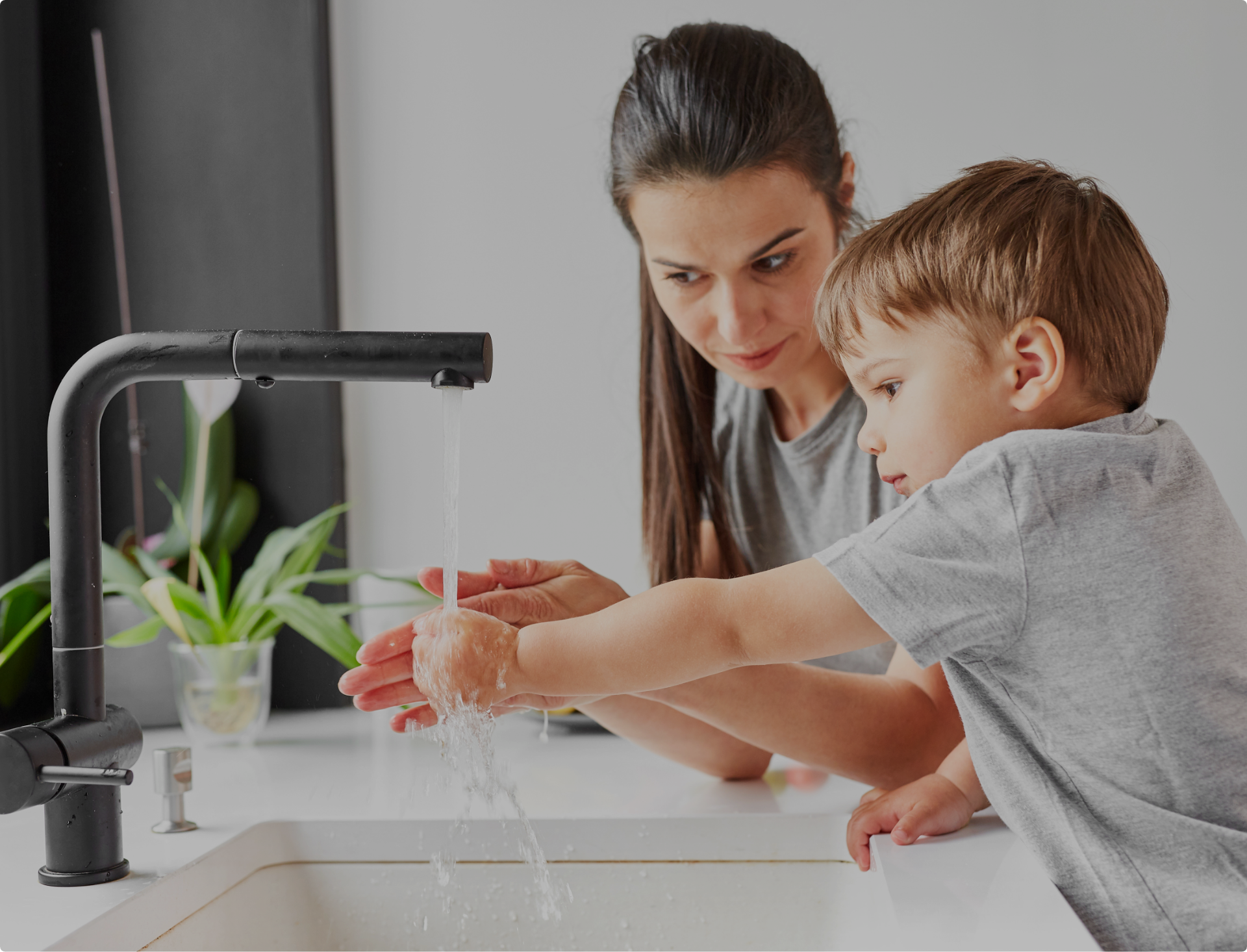 Parent and child washing hands at a kitchen sink
