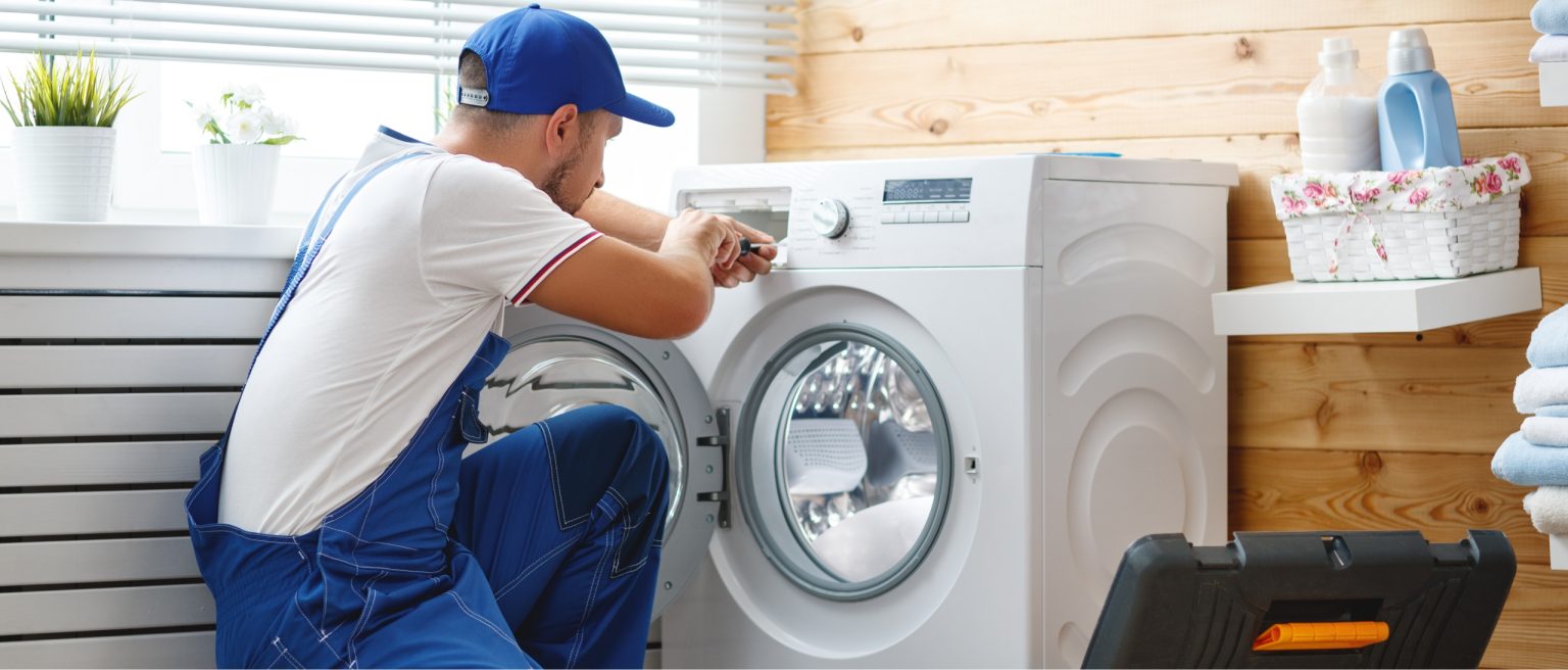 Technician fixing a washing machine in a laundry room